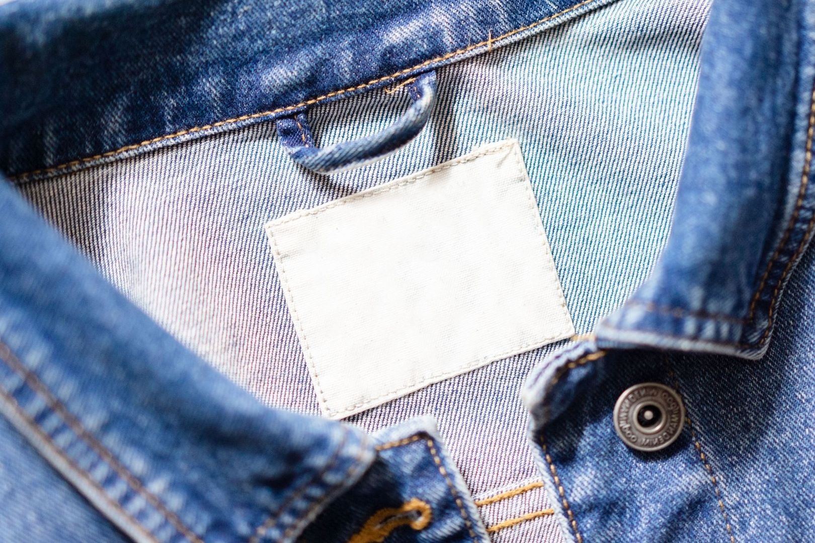 Närbild av en blank, vit tvättetikett i ett par blå jeans