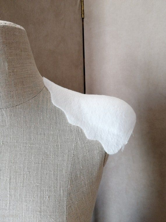 Vit axelvadd placerad på en beige skräddardocka