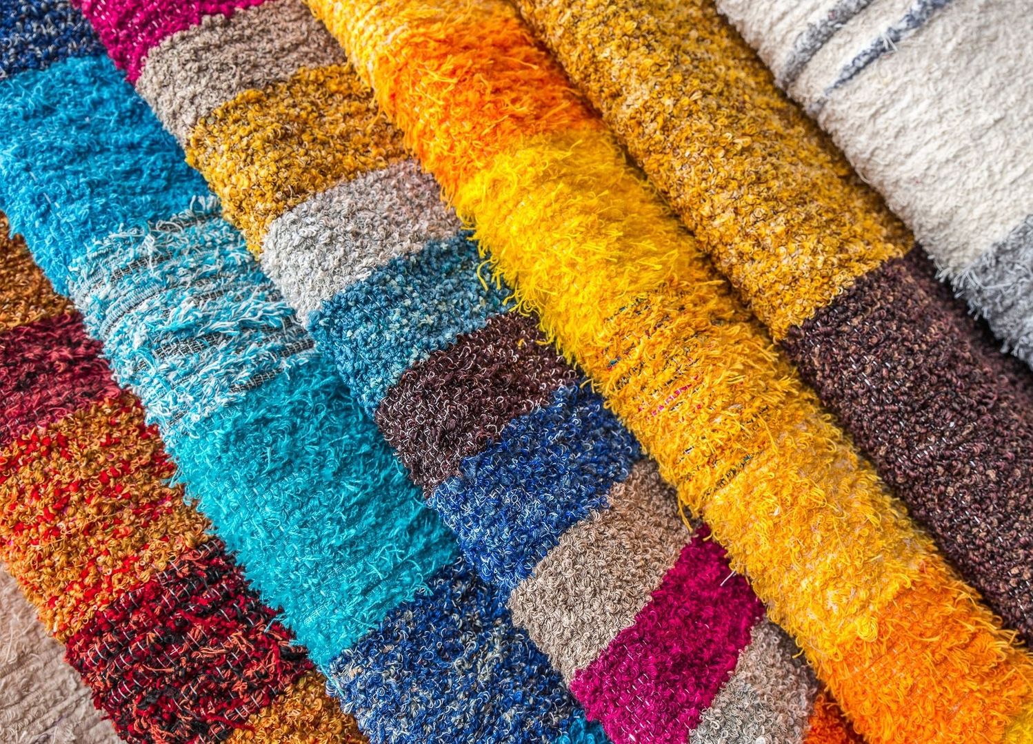 Närbild av färgstarka, texturerade tyger i många nyanser